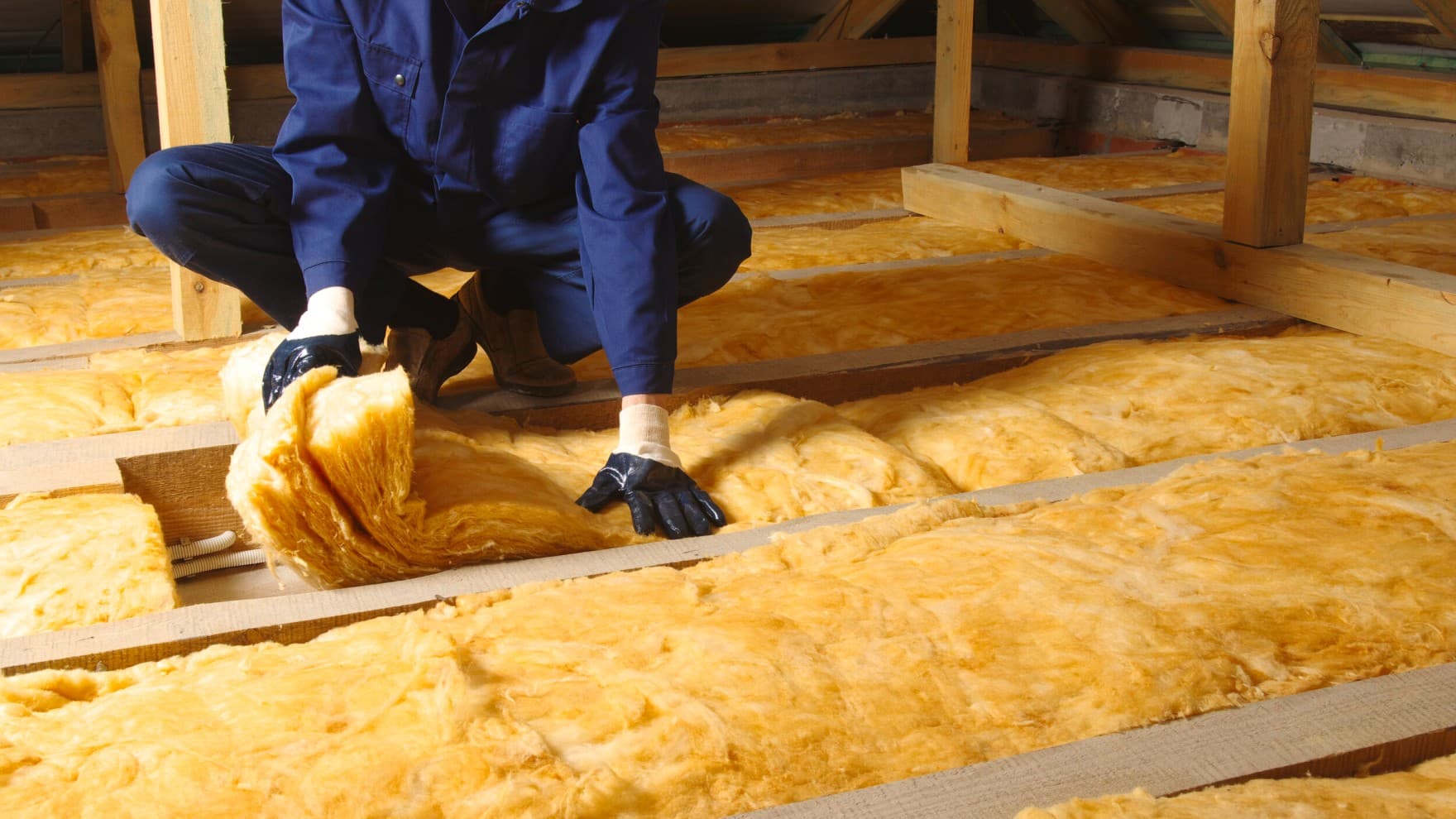 маж облечен во лична заштитна опрема инсталира подно греење