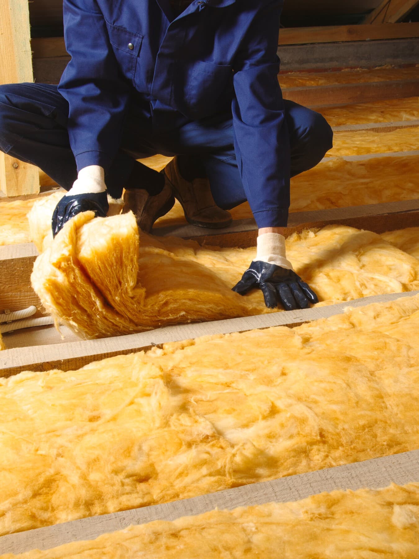 маж облечен во лична заштитна опрема инсталира подно греење