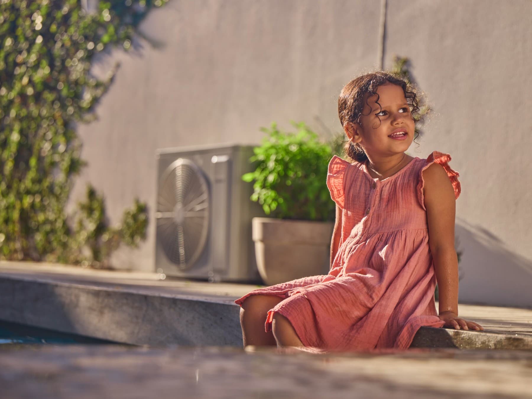 Девојка седи во градината до топлинска пумпа