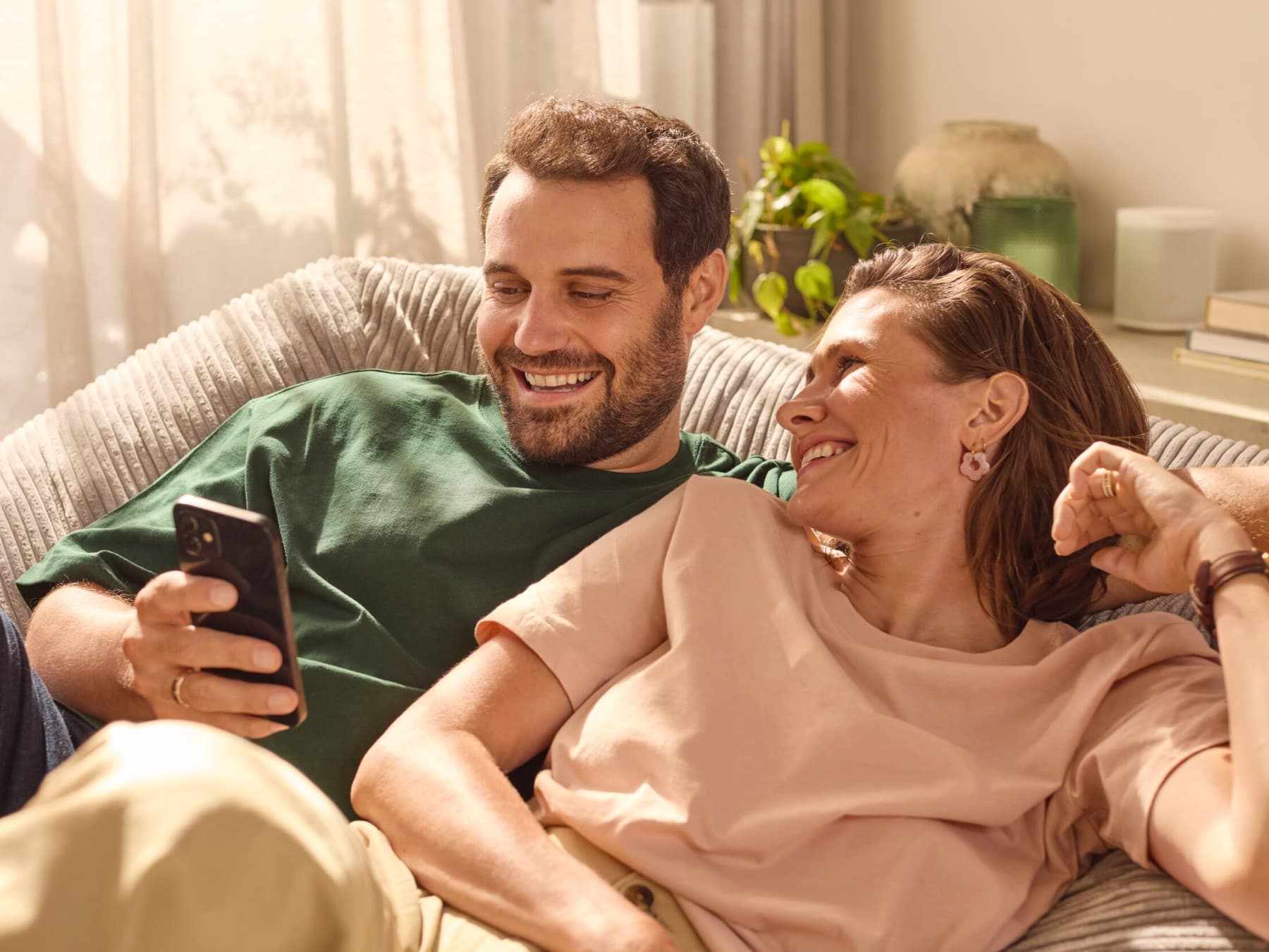 Пар седи на софата и ја проверува потрошувачката на енергија преку апликација