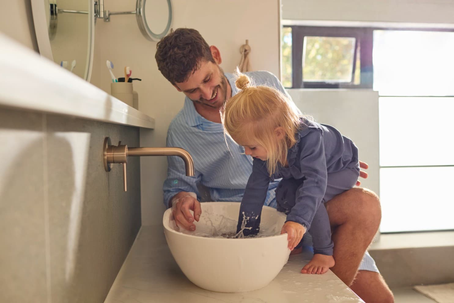Татко и ќерка си играат со вода во мијалник