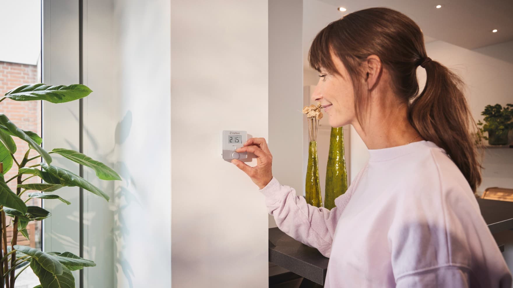 Жена го користи термостатот Vaillant sensoROOM