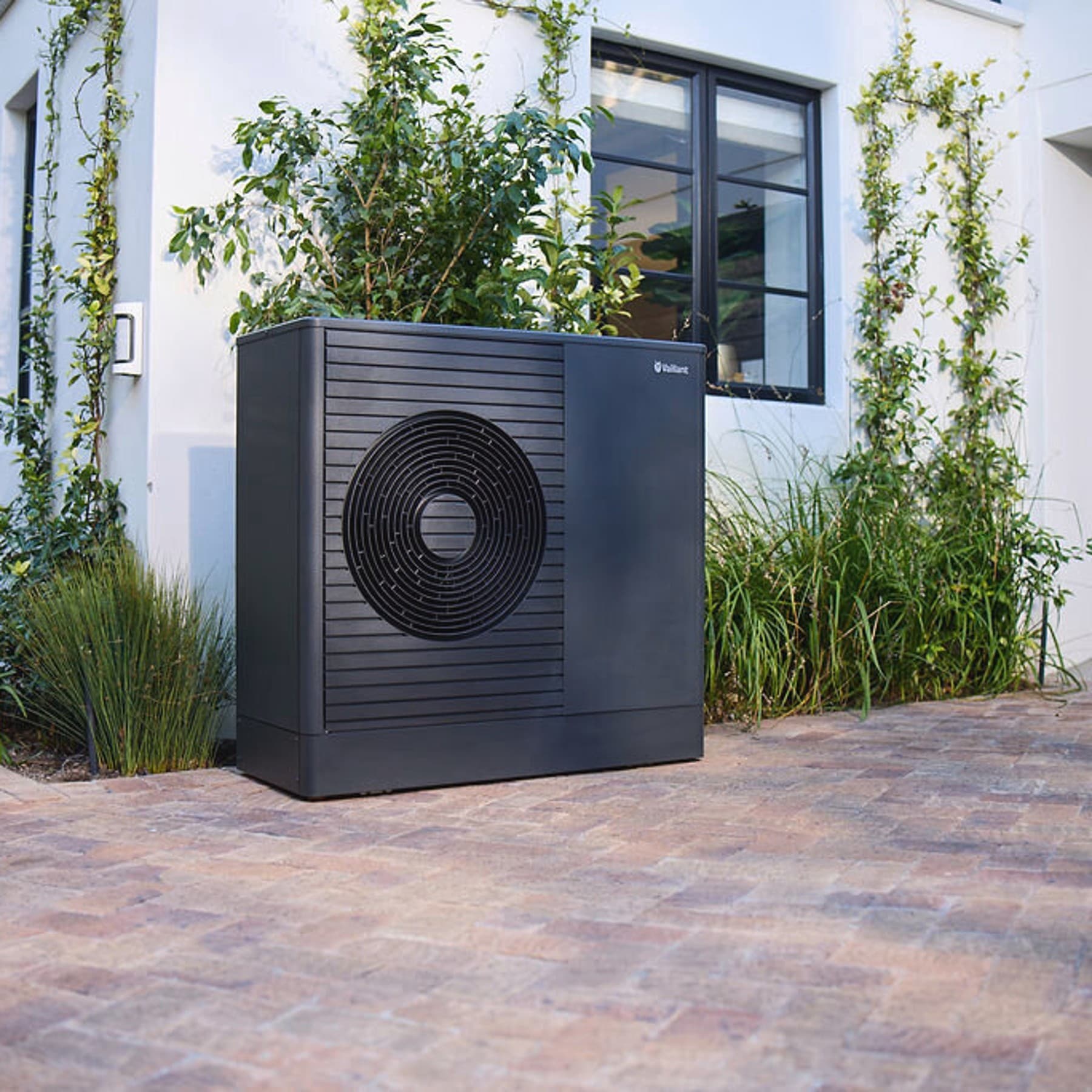 Темна топлинска пумпа Vaillant aroTHERM plus во предната градина на куќата