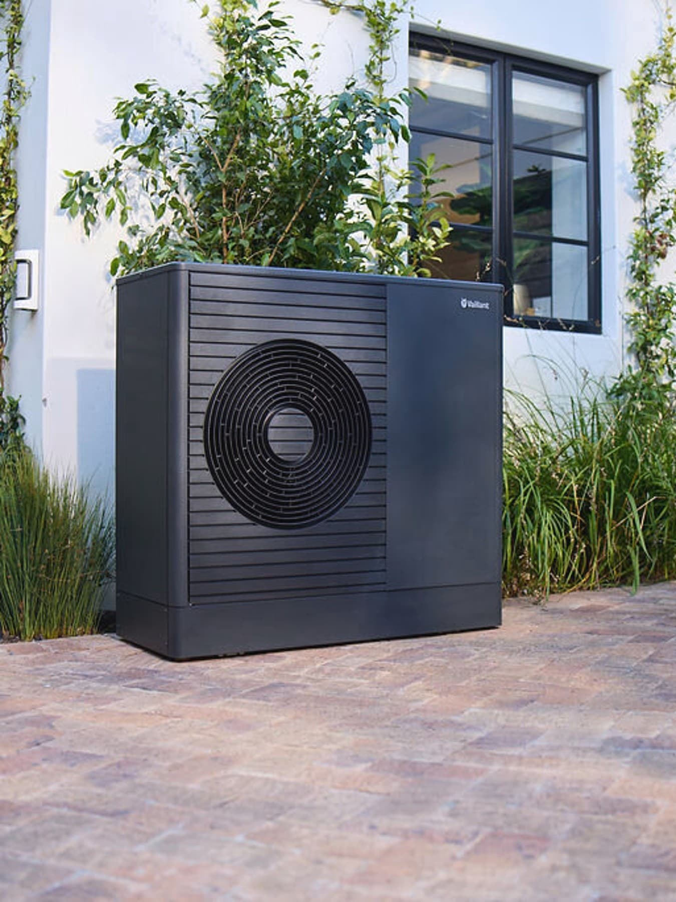 Темна топлинска пумпа Vaillant aroTHERM plus во предната градина на куќата