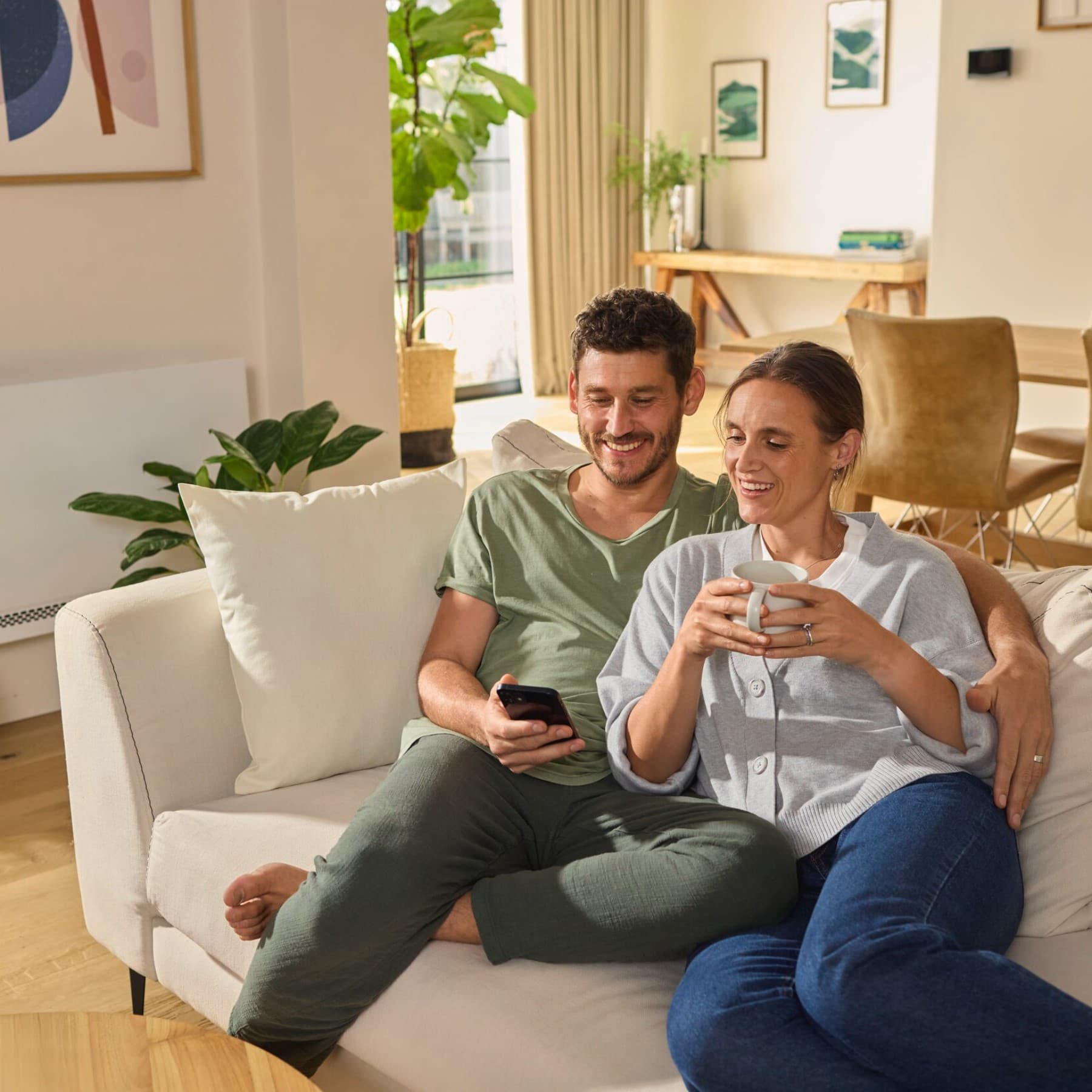 Пар седи на софата гледајќи во паметен телефон