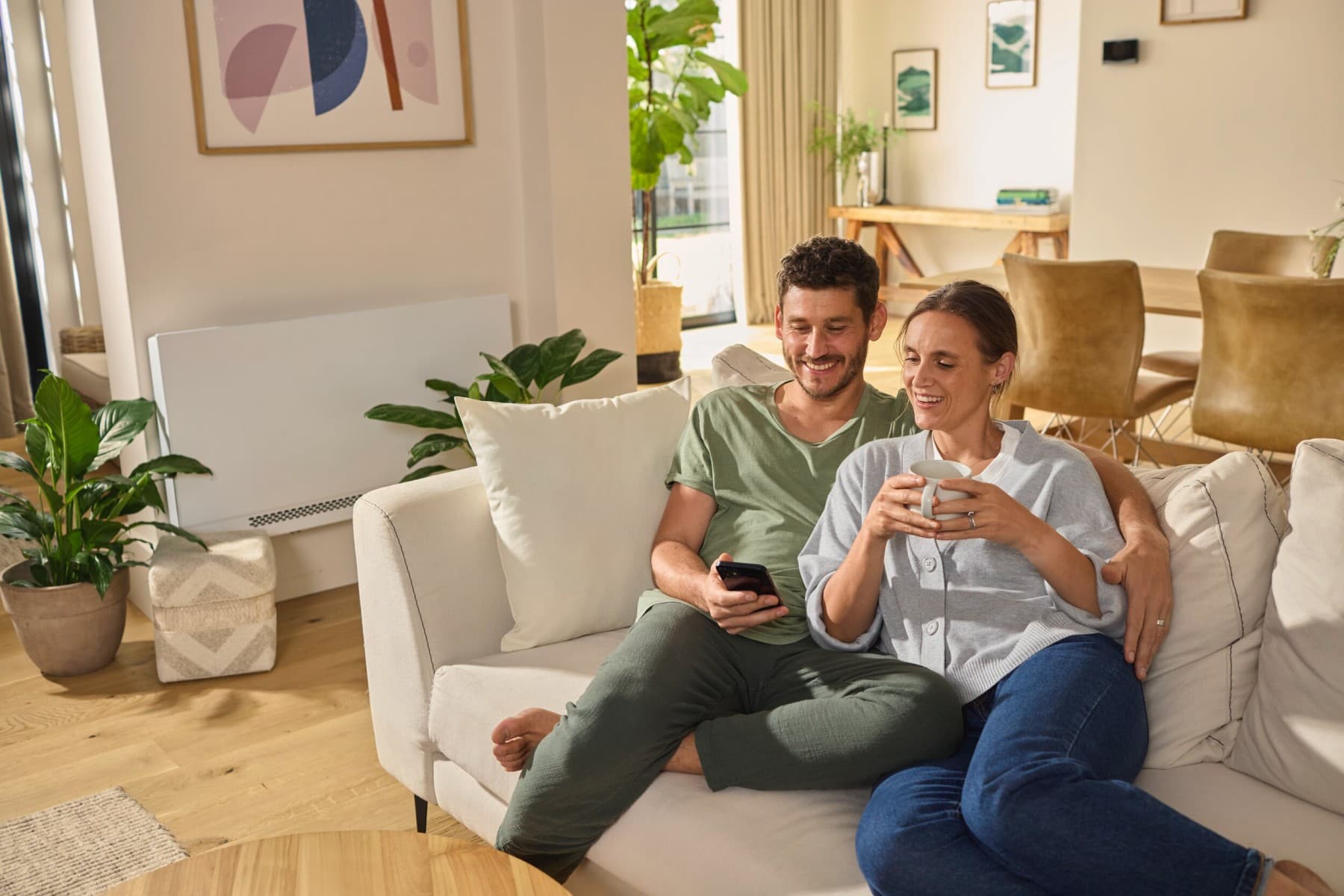 Пар седи на софата гледајќи во паметен телефон