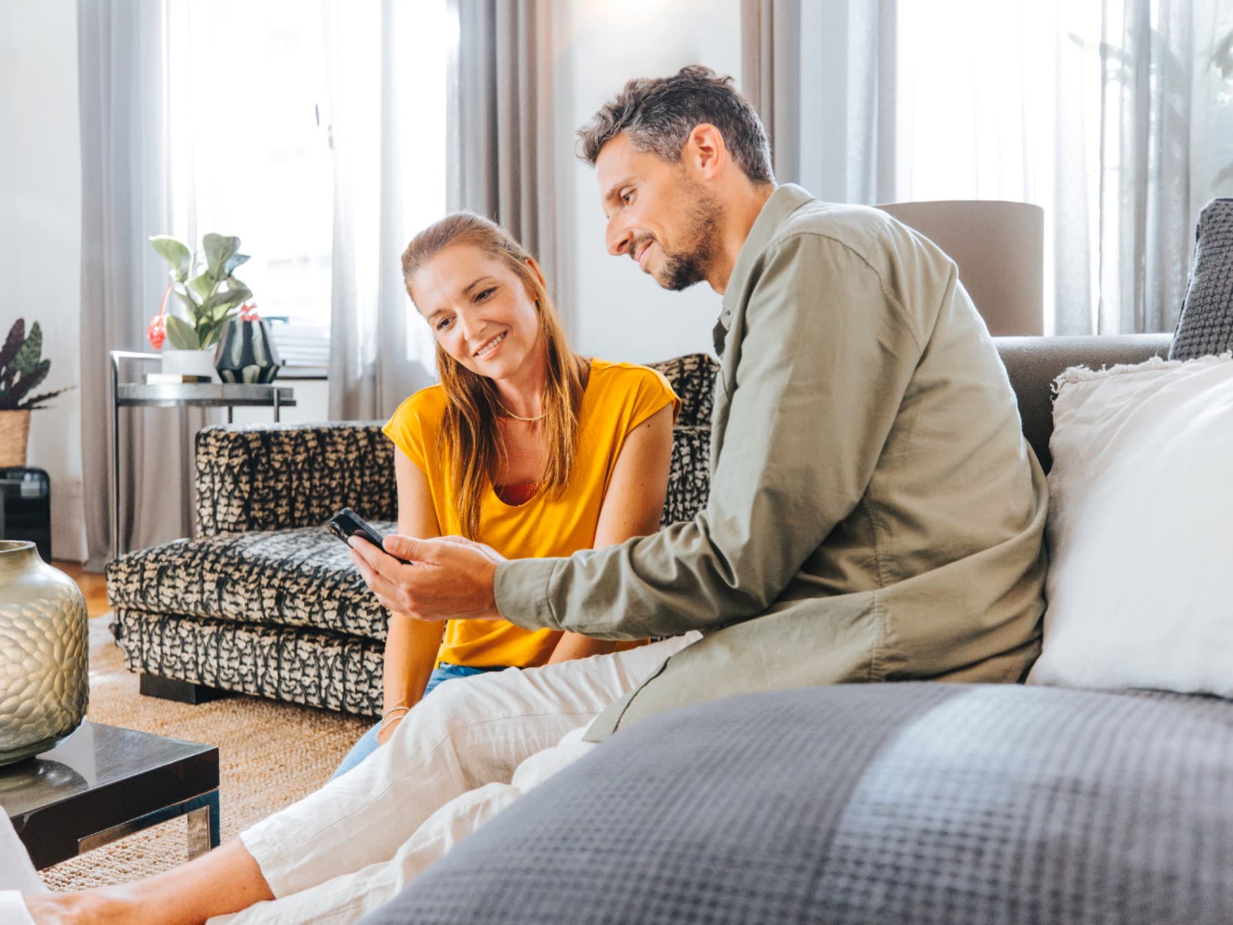 Пар на софа гледајќи мобилен телефон
