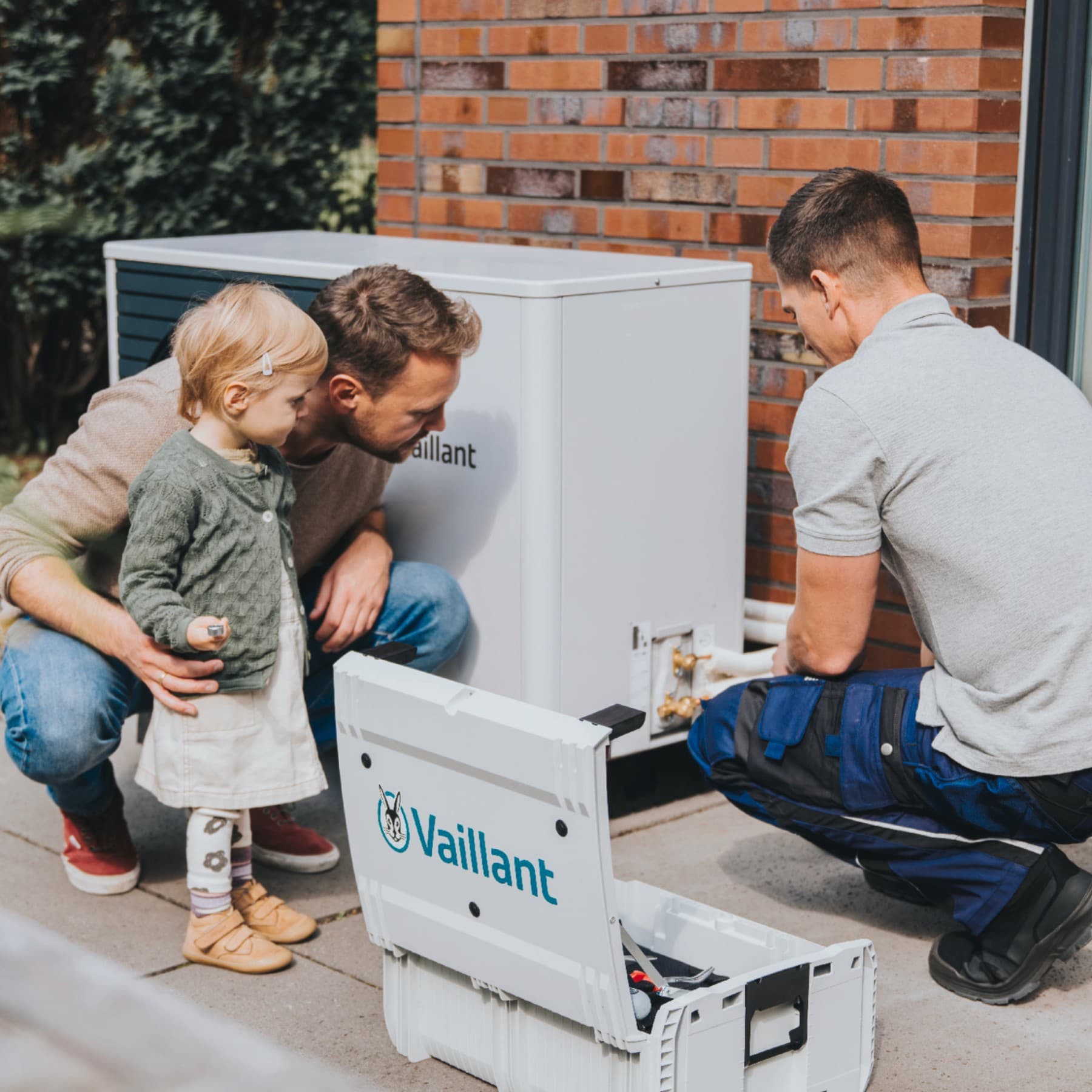Татко и ќерка гледаат како инсталатер сервисира топлинска пумпа