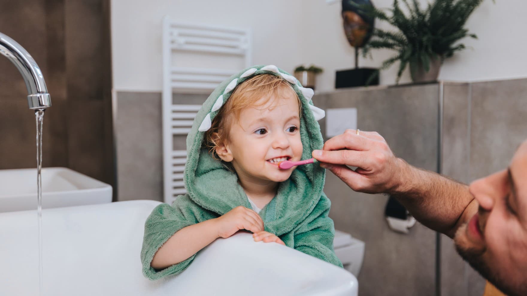 Татко мие заби на дете со загреан држач за пешкири во позадина