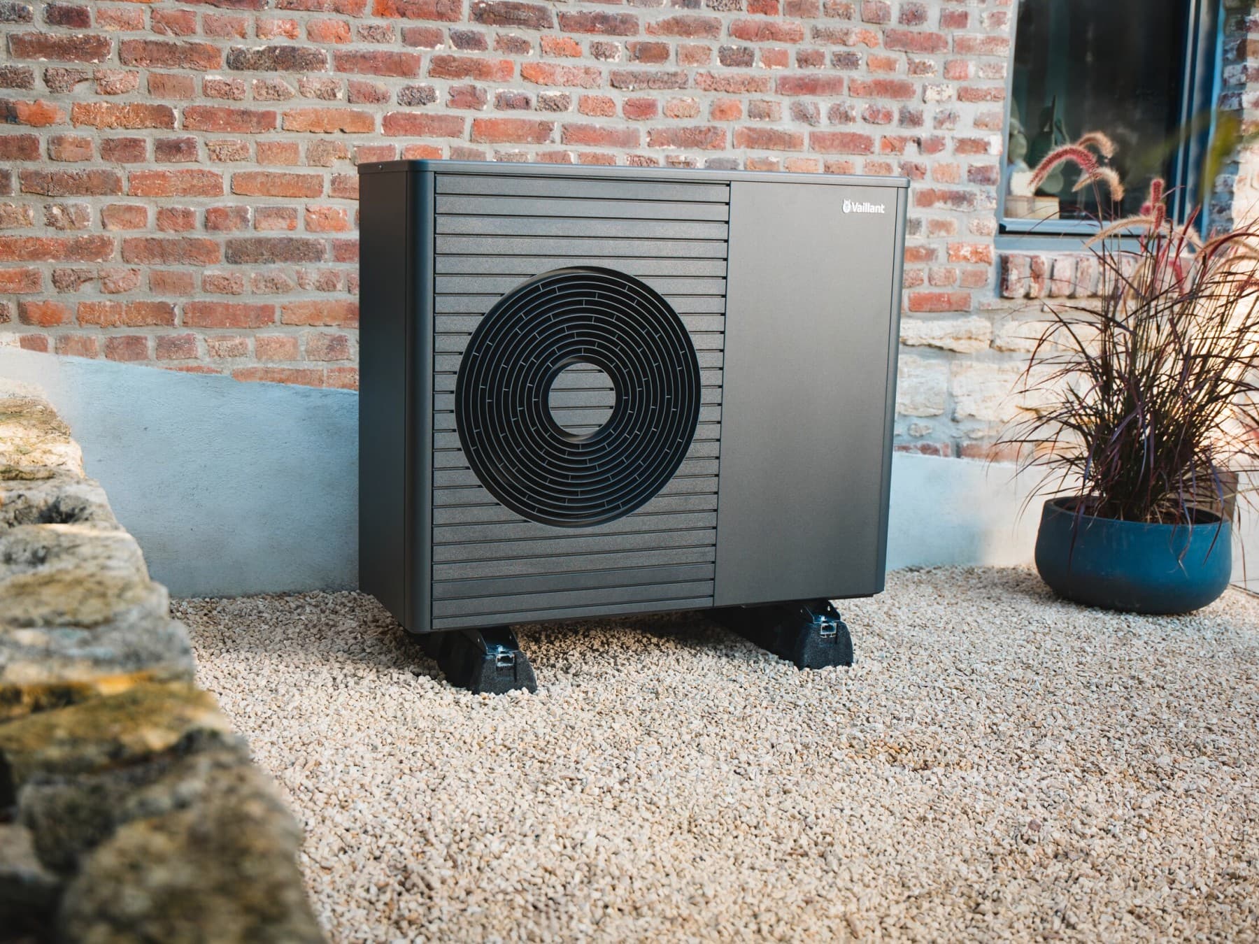 Надворешна топлинска пумпа поставена пред ѕидот на куќата.