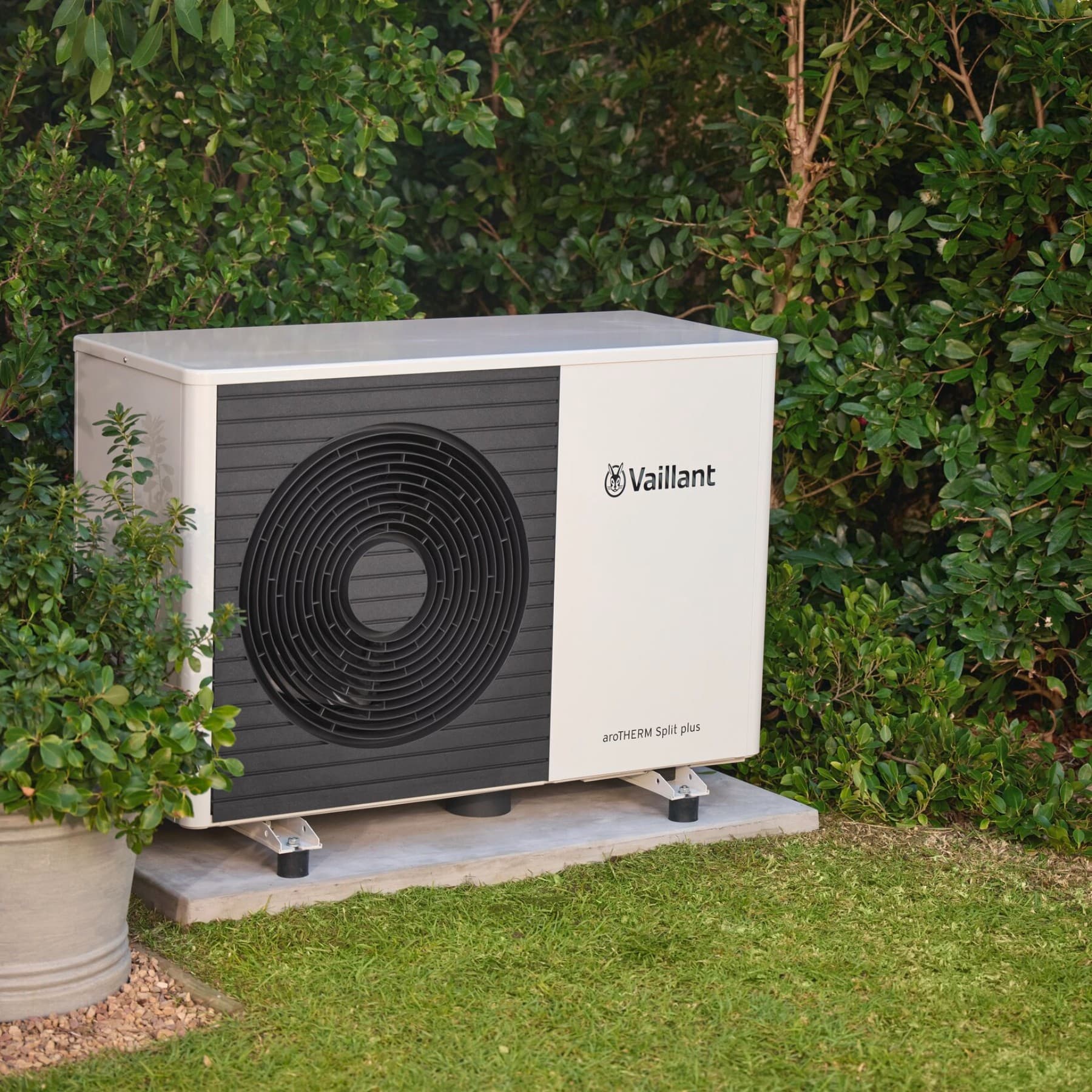 Топлинска пумпа пред жива ограда од градина