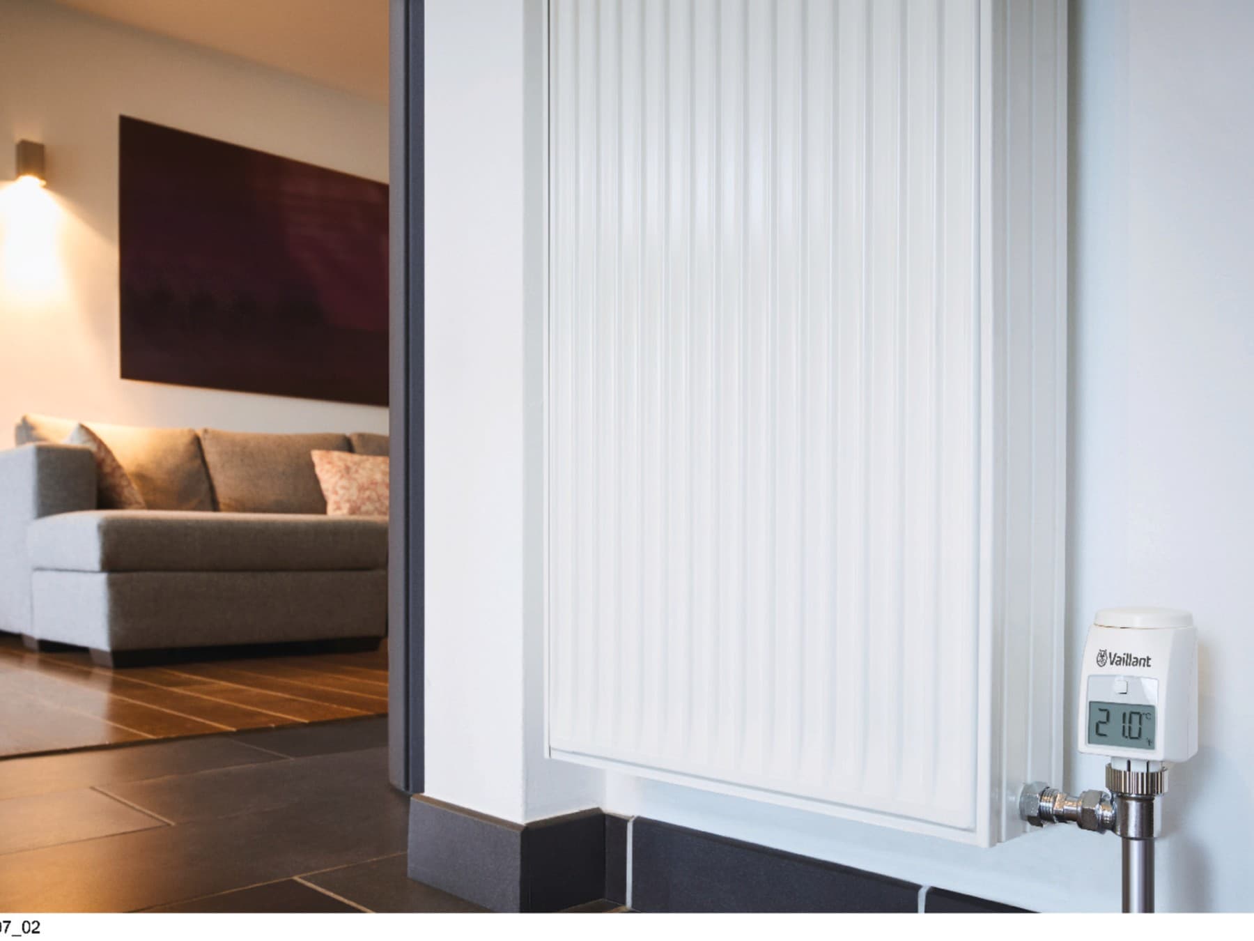 Радијатор со кауч и пријатна светлина во позадина, екранот на радијаторот покажува 21°