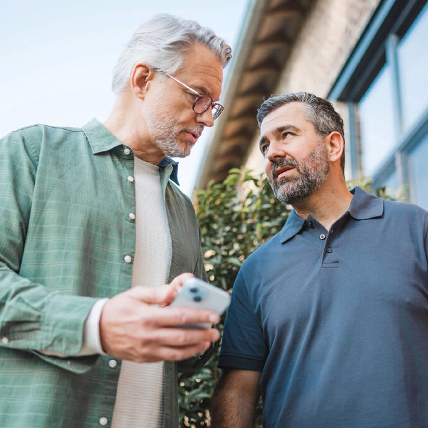 Човек му покажува нешто на инсталатерот на својот паметен телефон