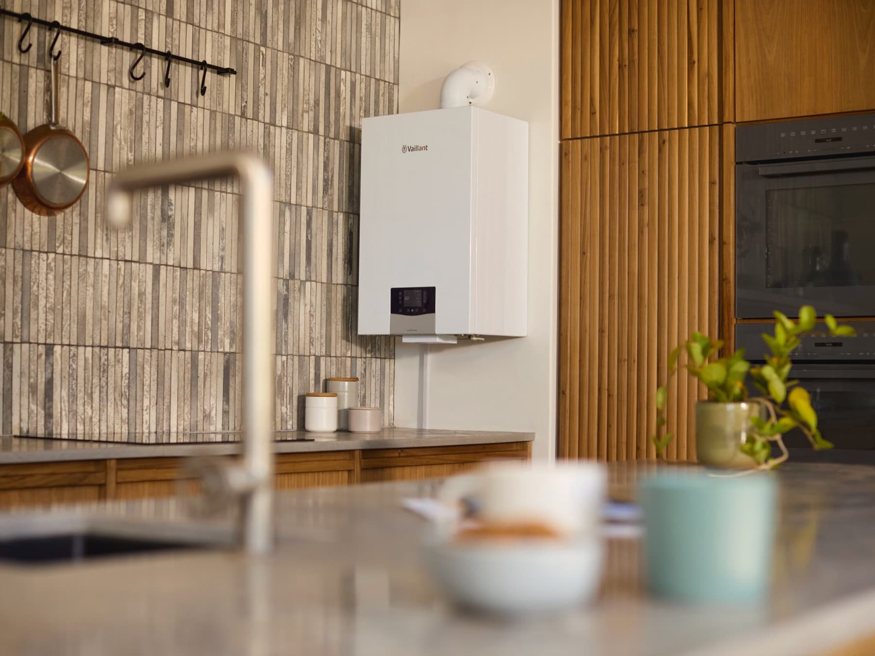 Бојлер на кујнски ѕид со мијалник во преден план