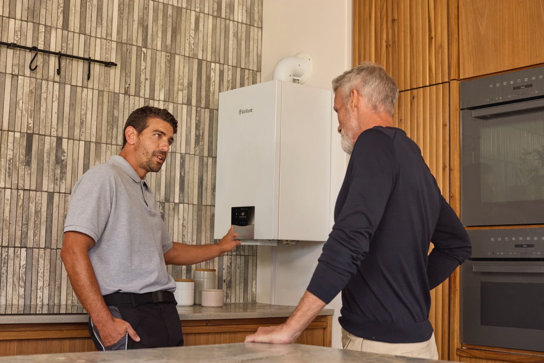 Инсталатер покажува на котел и му објаснува на клиентот